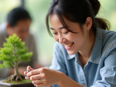 ワークショップで笑顔で盆栽の手入れをする参加者のクローズアップ。手元にはミニチュアの剪定バサミが見える。